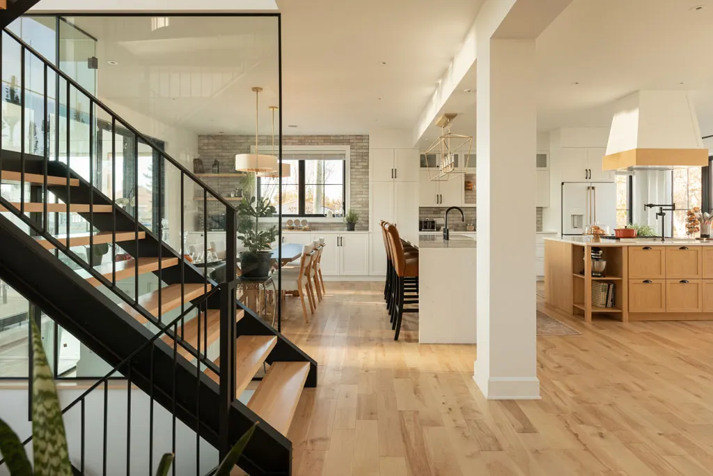 Salle à manger et cuisine — Rénovation résidentielle | Rénovation Julien Dubé Vue d'ensemble depuis l'escalier vitré vers la salle à manger et la cuisine à dosseret de pierre