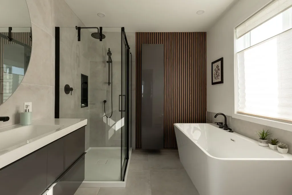 Vue d'ensemble de la salle de bain : douche vitrée, mur de lattes et baignoire sous la fenêtre