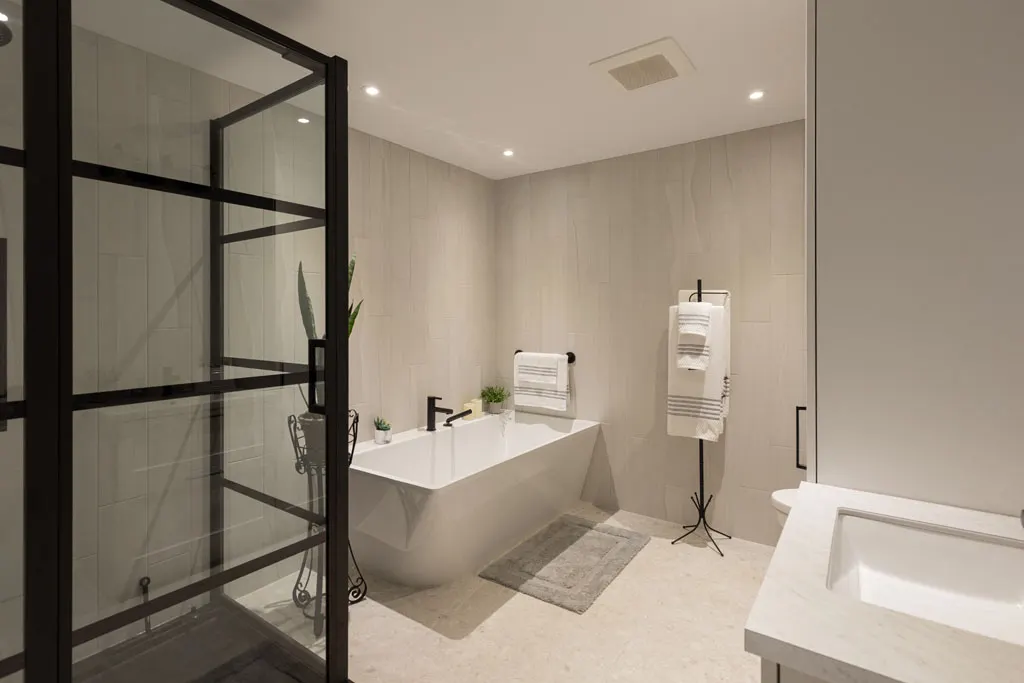 Bain autoportant et douche vitrée — Rénovation Julien Dubé, entrepreneur général à Repentigny Salle de bain grise : bain autoportant blanc, douche vitrée à cadre noir et valet à serviettes en métal noir